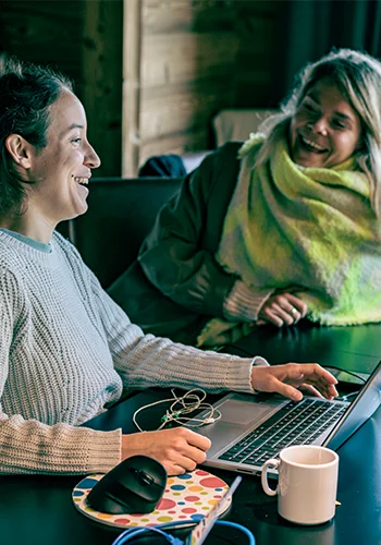 Zwei Frauen sitzen lachend vor einem Computer